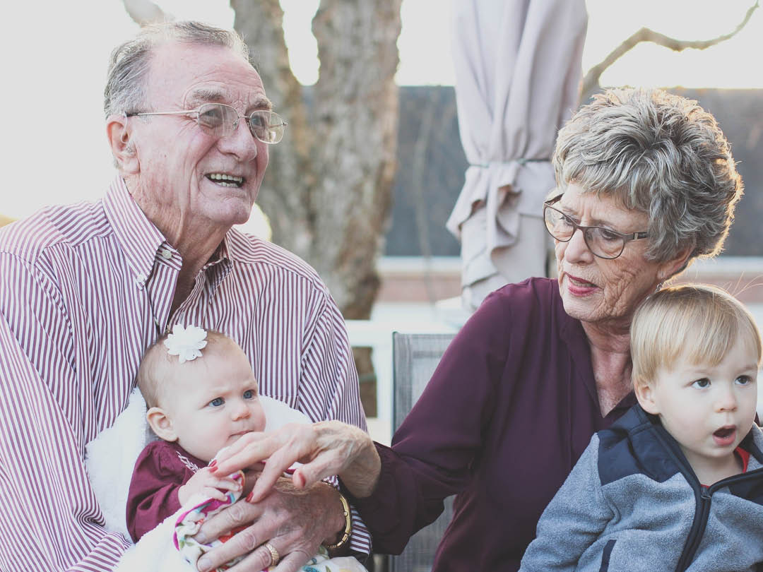 Elderly couple holding two grandchildren